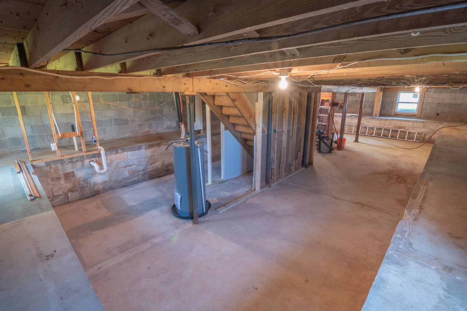 A tank water heater in an unfinished basement with exposed beams